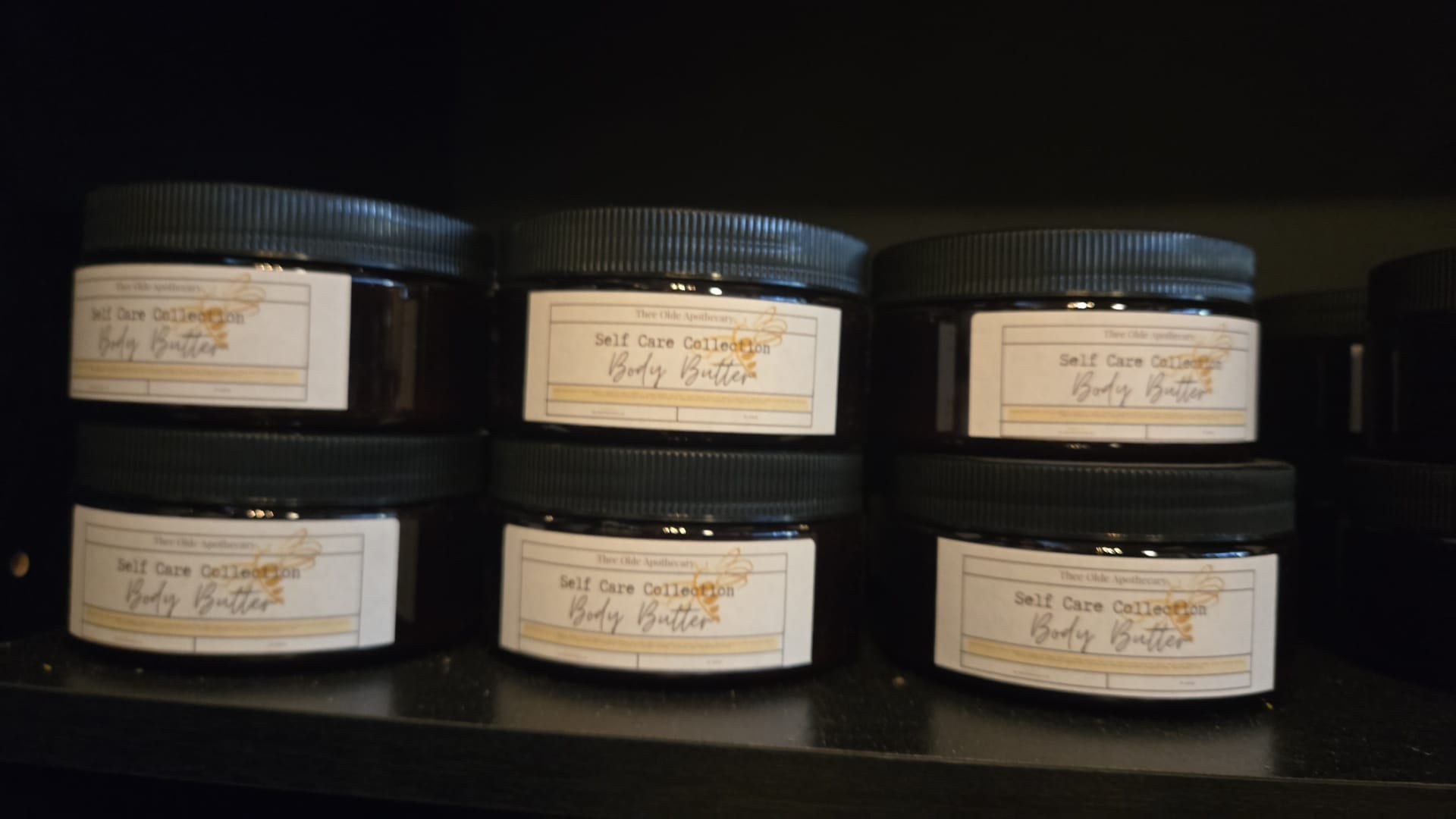 Jars of body butter on a shelf with labels.